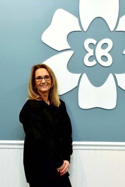 Eric Batterton DDS Betty Smith standing by Dr. Batterton's logo wall